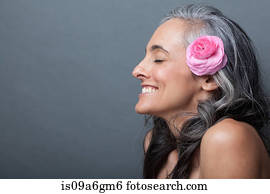 Mature woman with pink flower in hair, eyes closed