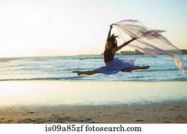Young woman dancing on sunlit beach
