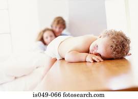 Baby resting with parents in the background