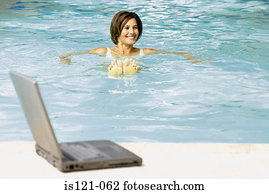 Woman in swimming pool with computer