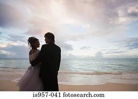 Newlyweds on beach at sunset