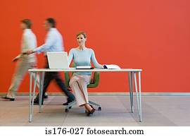 Men walking past woman at desk