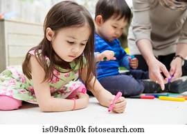 Mother and two children drawing in garden