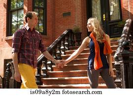 Couple walking hand in hand past outdoor stairs