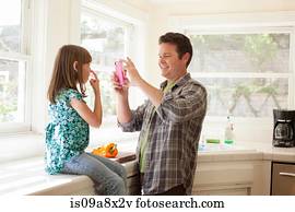 Father photographing daughter on smartphone