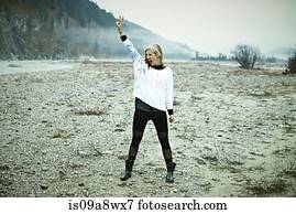 Woman standing in remote setting making peace sign