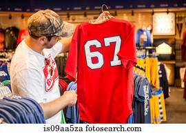 Man holding up t-shirt in store
