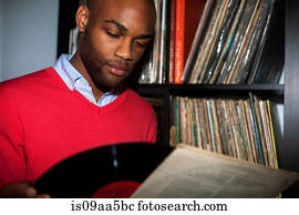 Portrait of young man removing vinyl record from sleeve