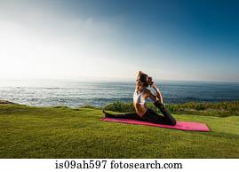 Women on cliff, in yoga position