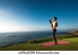 Women on cliff, in yoga position