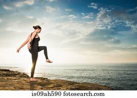 Women on cliff, in yoga position
