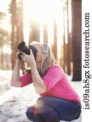 Mature woman photographing in forest