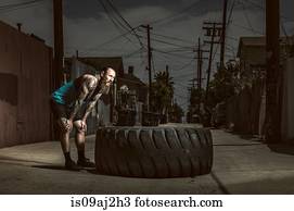 Mid adult man standing by large tire