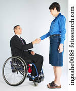 Businessman in wheelchair shaking woman's hand