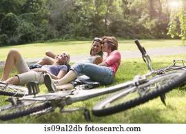 Three mature woman relaxing on grass after bicycle ride