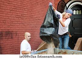 Couple filling skip with rubble