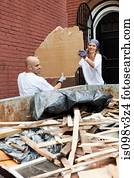 Couple filling skip with rubble