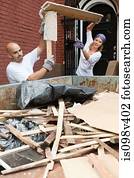 Couple filling skip with rubble