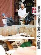 Couple filling skip with rubble