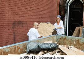 Couple filling skip with rubble