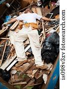 Man lying on top of pile of rubble in skip