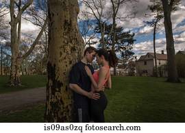 Romantic young sporty couple embracing in park at dusk