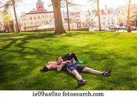 Romantic young sporty couple lying on grass in park