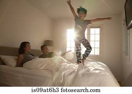 Boy jumping on parents bed