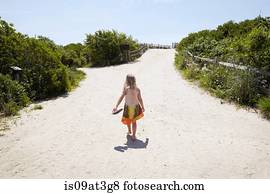 Rear view of girl walking barefoot to beach