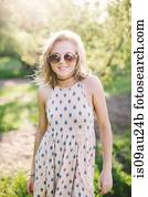 Young woman wearing sleeveless dress and sunglasses looking at camera smiling