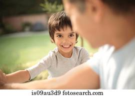 Boy in garden smiling at father, differential focus