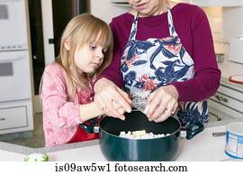 Girl and grandmother measuring salt for saucepan