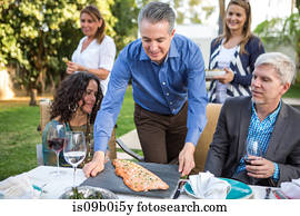 Mature man placing fish cuisine on garden party table