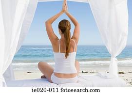 Woman practising yoga on a beach
