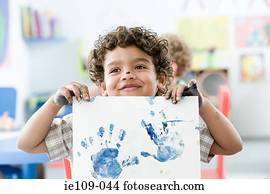 Boy holding up painted hand print