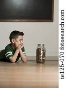 Boy looking at jar of money