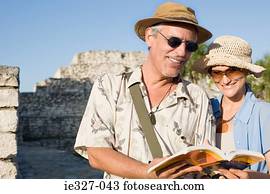 Couple by ruins with guidebook