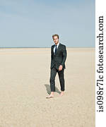 Businessman walking barefoot in the desert