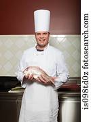 Male chef holding fish in commercial kitchen