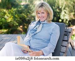 Mature woman on sun lounger with book