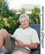 Senior man on sun lounger with book