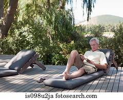 Senior man reading on sun lounger