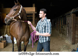Young man with horse at stable
