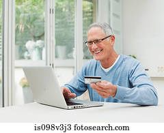 Senior man using laptop with credit card