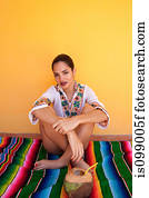 Woman sitting on ethnic style blanket with tropical fruit juice