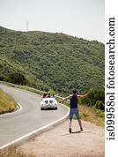 Convertible car driving past hitchhiker