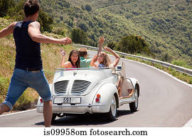 Convertible car driving past hitchhiker