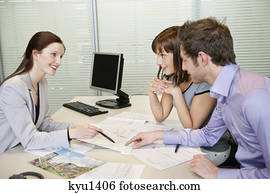 Female real estate agent showing a brochure to a couple