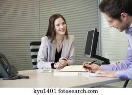 Man signing documents with a female real estate agent sitting in front of him