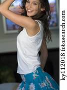 Young woman in white tank top dancing, smiling for the camera